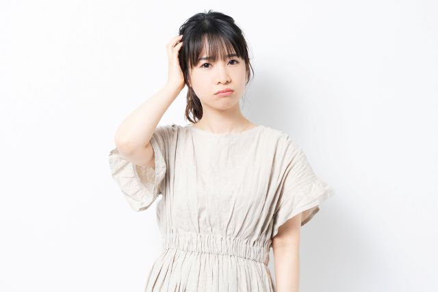 頭をおさえて悩む女性